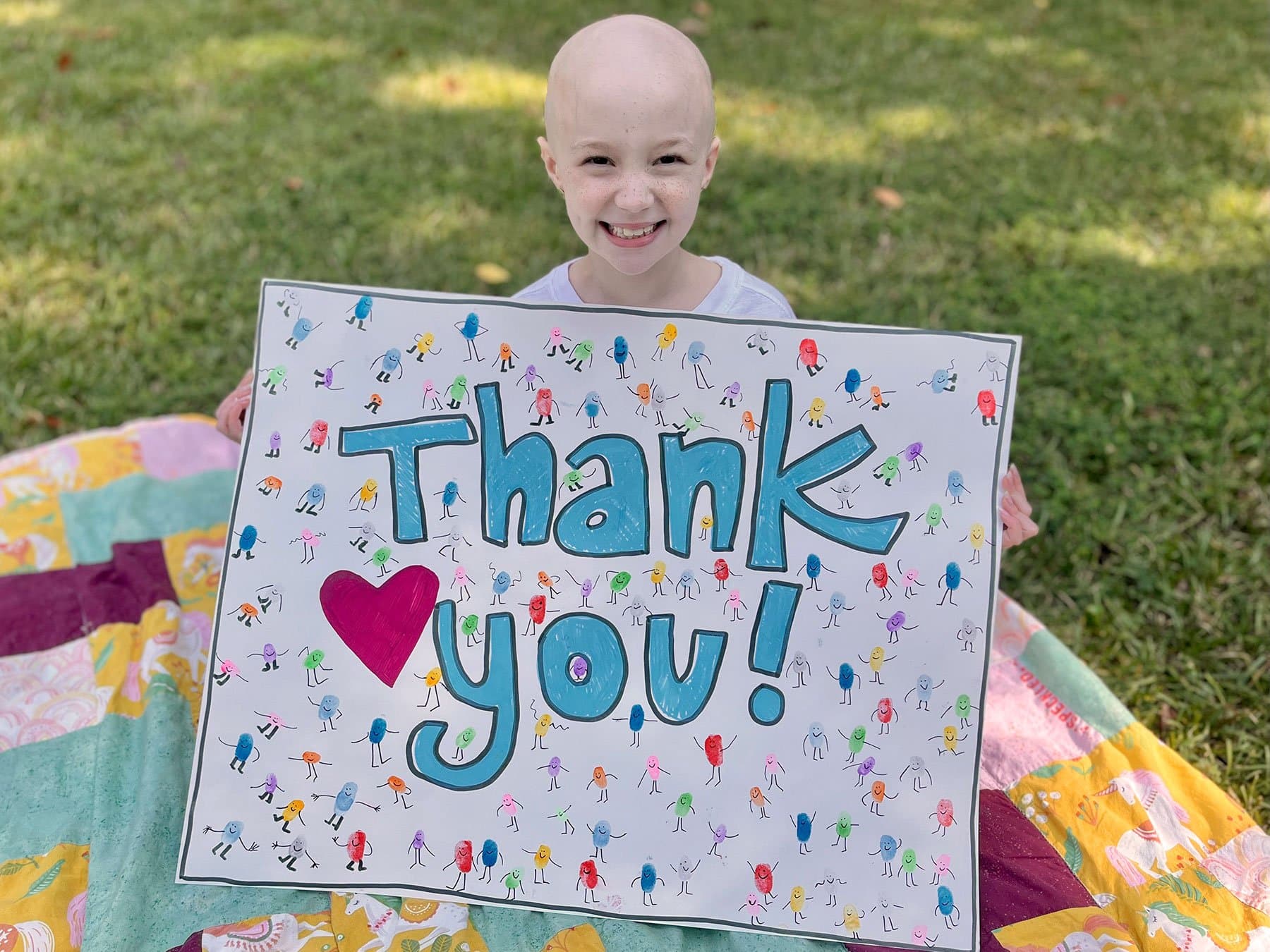 Image of Harper Harrell, a cancer thriver, holding a thank you poster