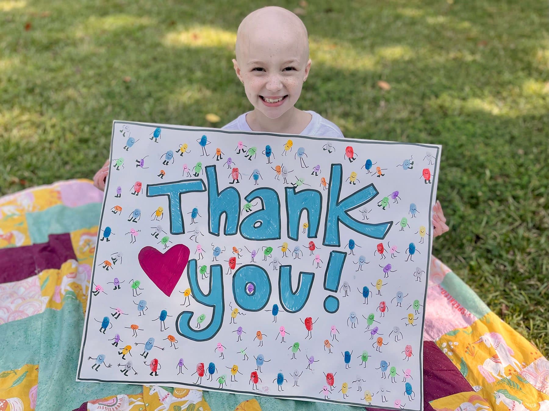 Image of Harper Harrell, a cancer thriver, holding a thank you poster